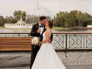 Bride and groom kissing beneath a clear umbrella