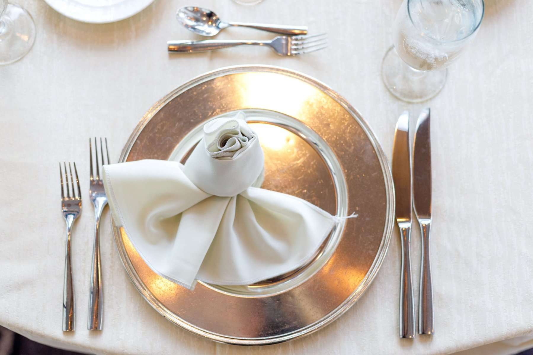 Silver charge plate with white linens