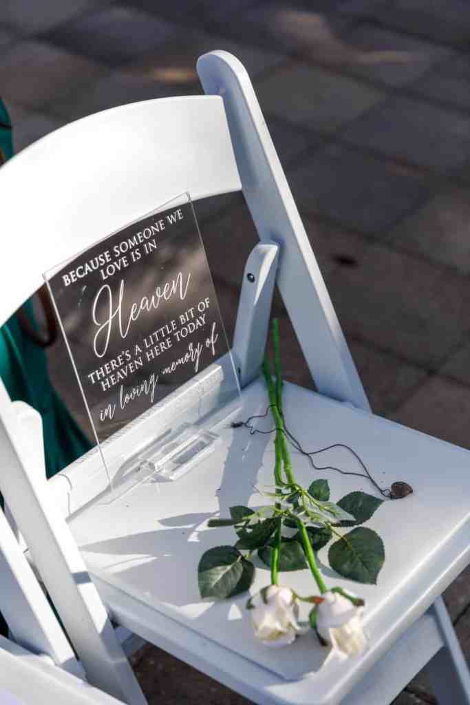 Memorial chair with sign and white rose at a wedding ceremony