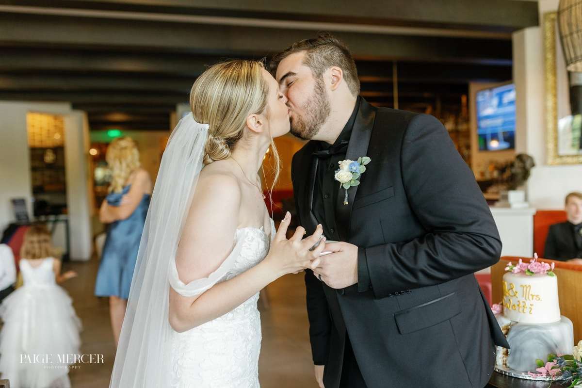 Bride and groom kissing after cutting their wedding cake