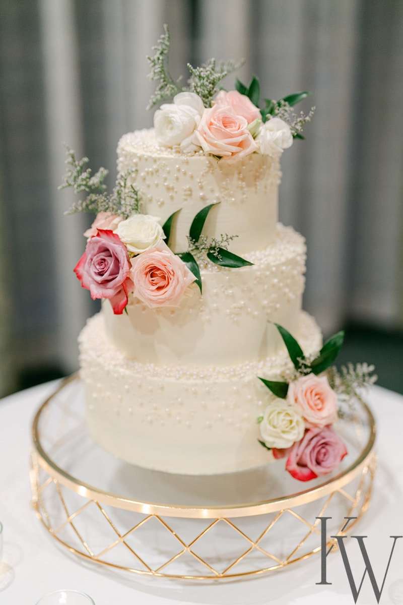 Three-tiered wedding cake topped with pink floral