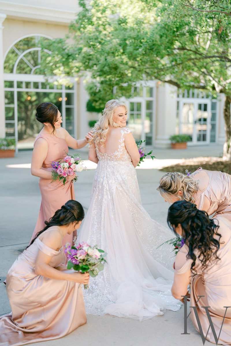 Bridesmaids helping to straighten the bride's skirt for a photo