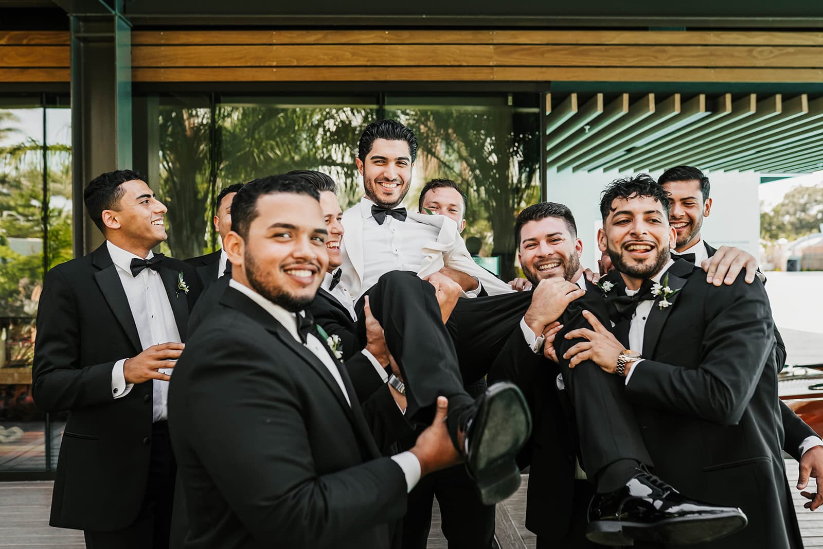 Groomsmen lifting a groom in front of the Chris-Craft Room at Evermore Orlando Resort