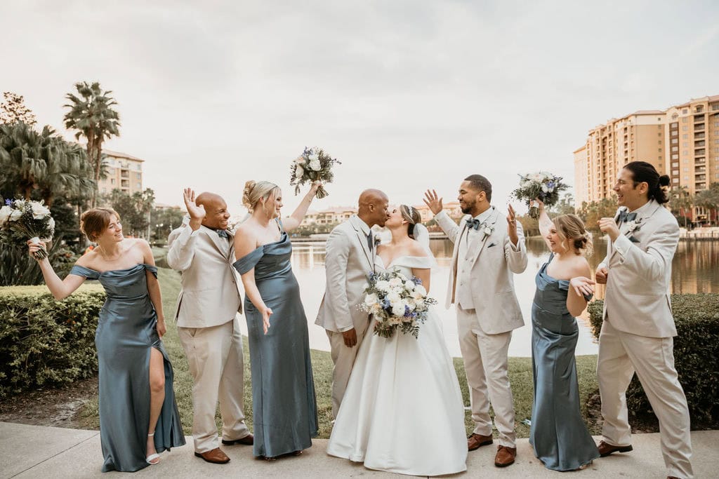 Bride and groom kissing in front of their wedding party