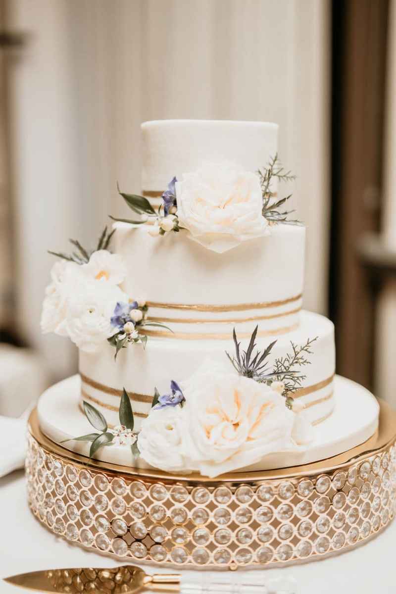 Three tiered white and gold wedding cake with fresh floral