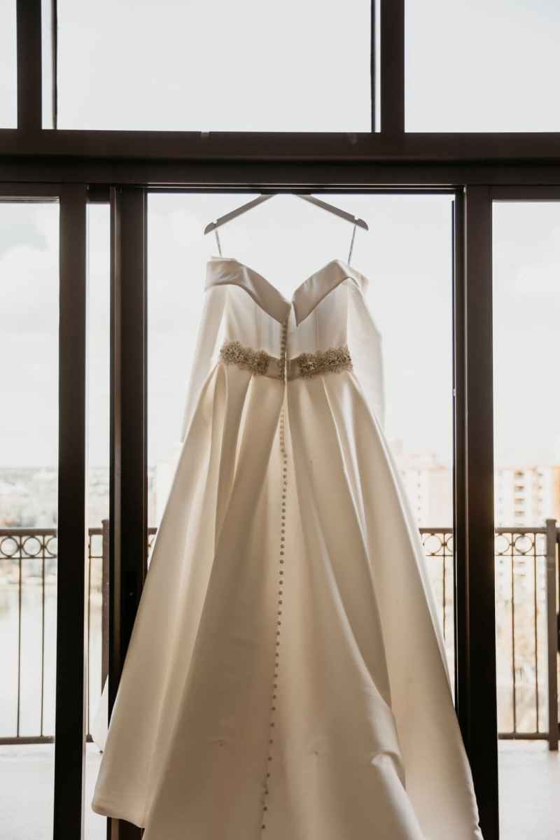 Wedding gown hanging in front of a window