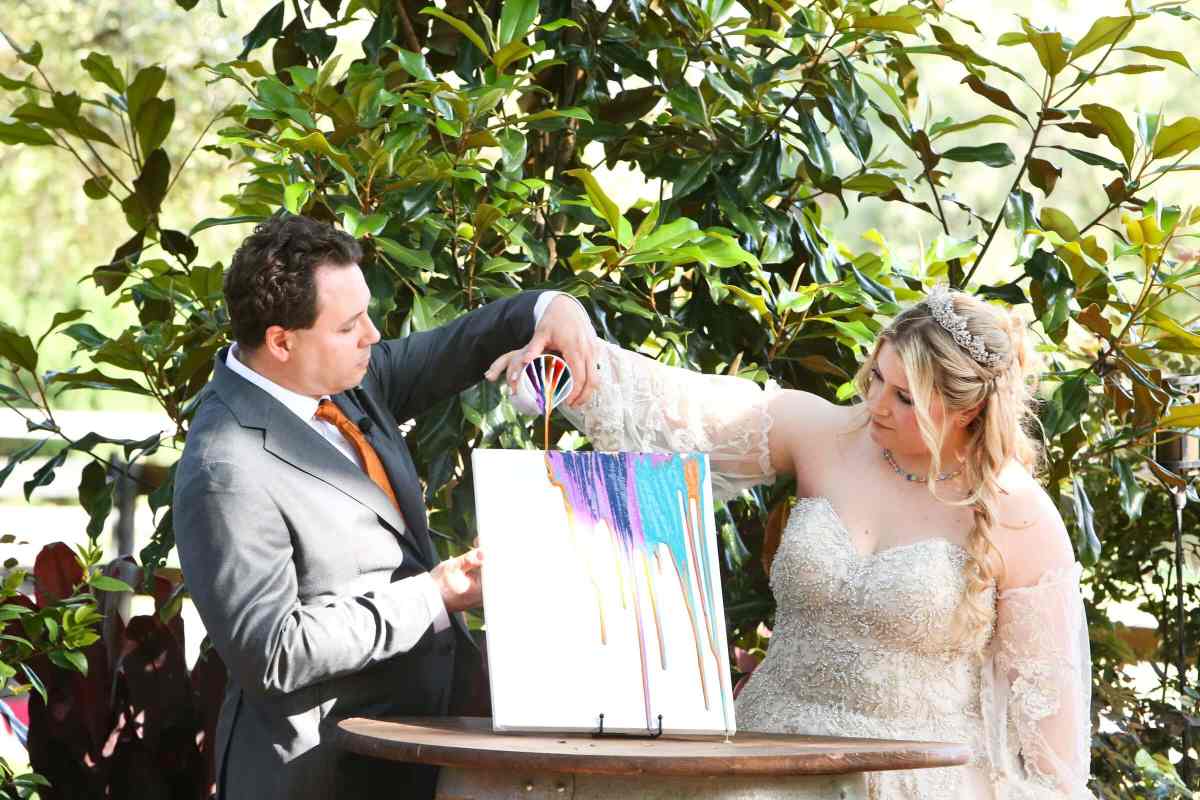 Bride and groom pouring colorful paint over a canvas