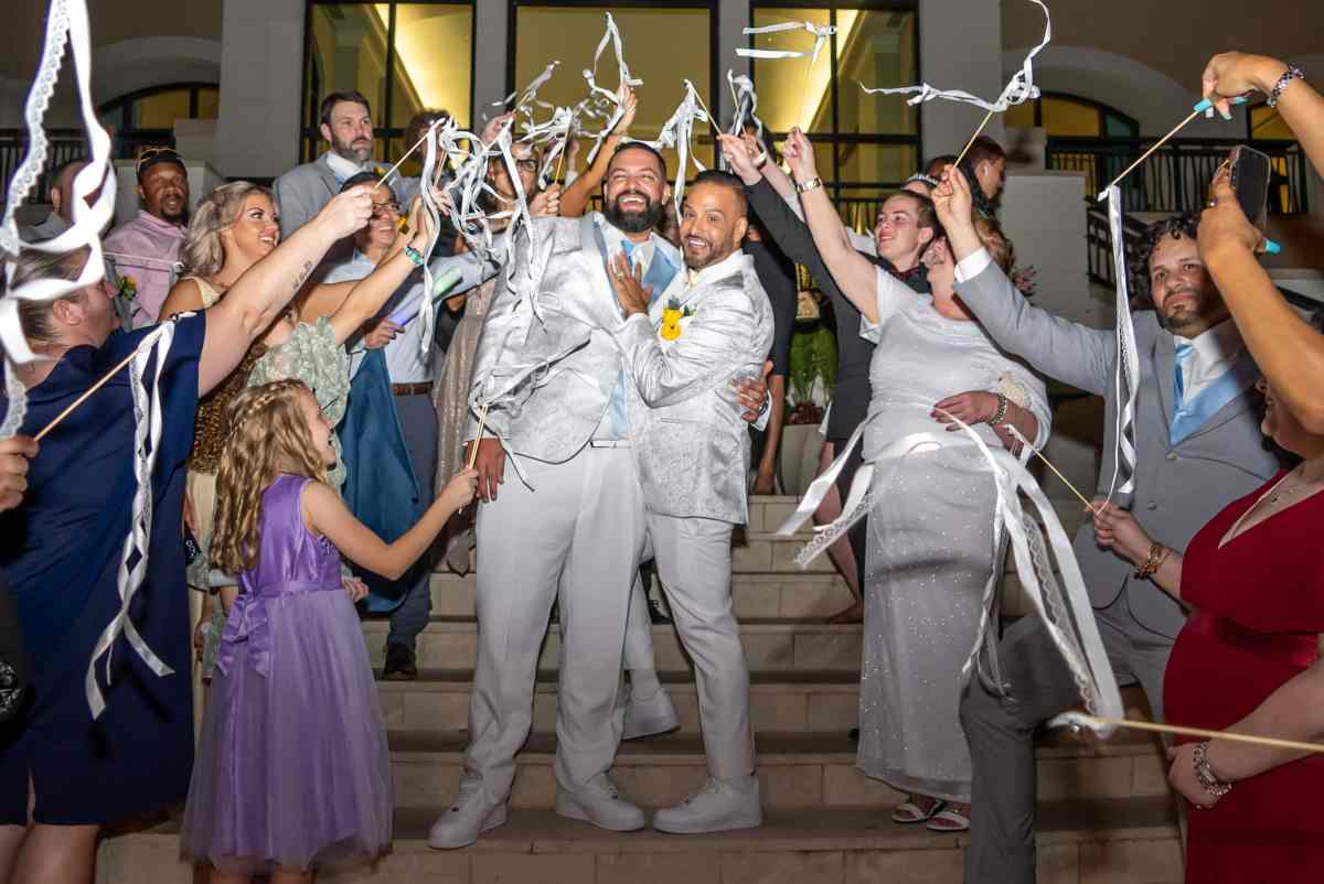 Two grooms having their grand exit with waving ribbons