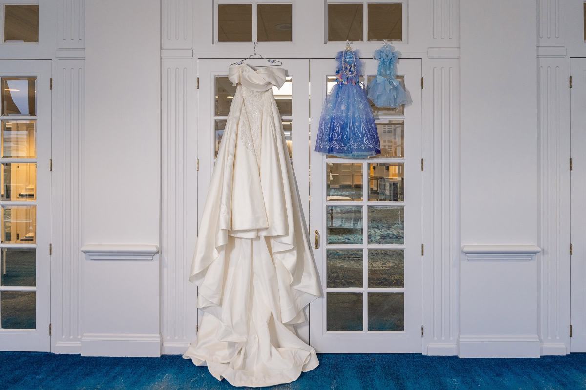 Bride's wedding gown hanging with two flower girls' dresses