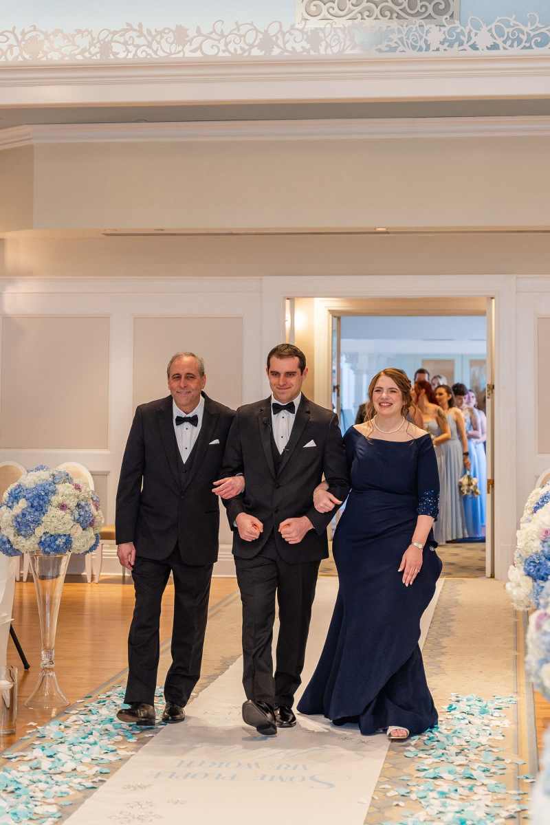 Groom being escorted up the aisle by his parents
