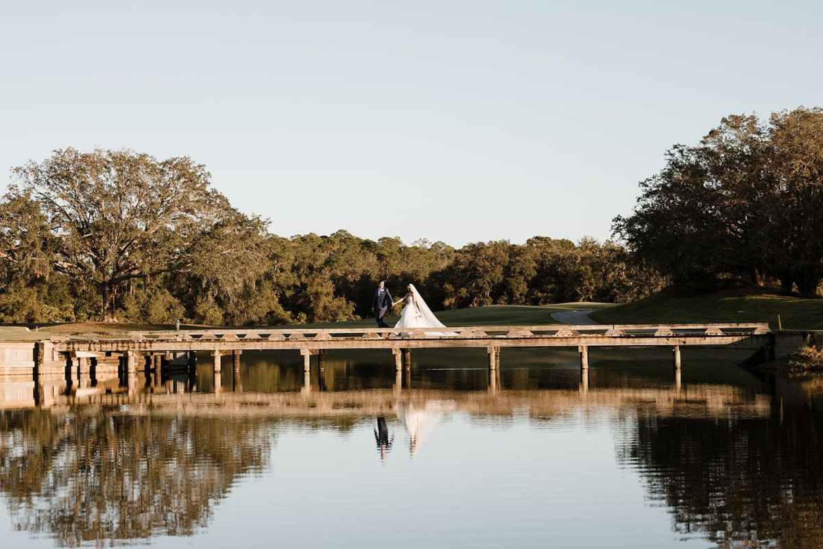 bride and groom walking across bridge